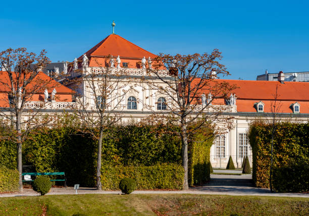 Belvedere Baroque palace in Vienna seen from the public gardens with fountains and dark clouds above.