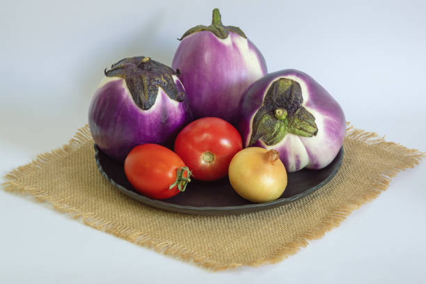 Vegetables. Eggplants, tomatoes and onion on black plate.  Copy space