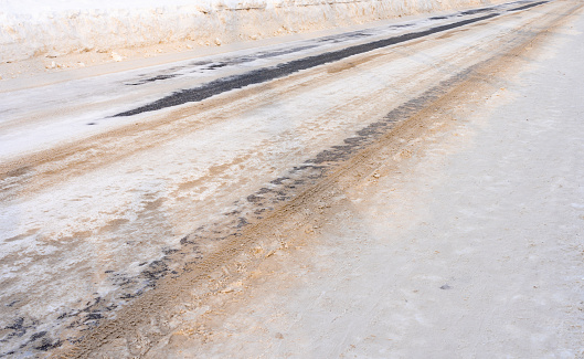 Winter road covered with snow and sprinkled with sand.