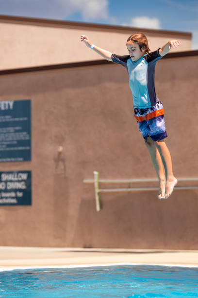 istock Young boy jumps off diving board at swimming pool 1426004559