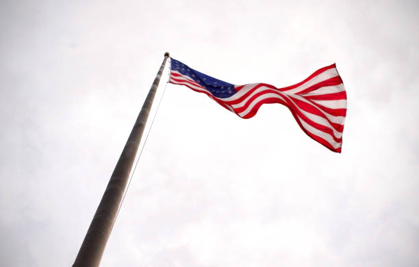 istock american flag, from below, seen blowing in wind on a flagpole in white sky 1426008259