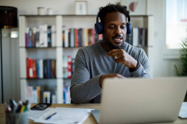 Man with headphones attends an online course at home stock photo