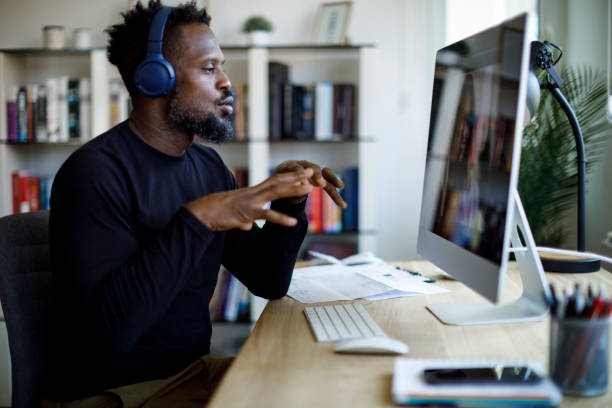 Man with headphones having video call at home office stock photo
