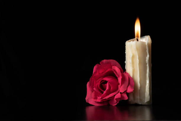 istock LIGHTED CANDLE AND RED ROSE ON DARK BACKGROUND. 1426024549
