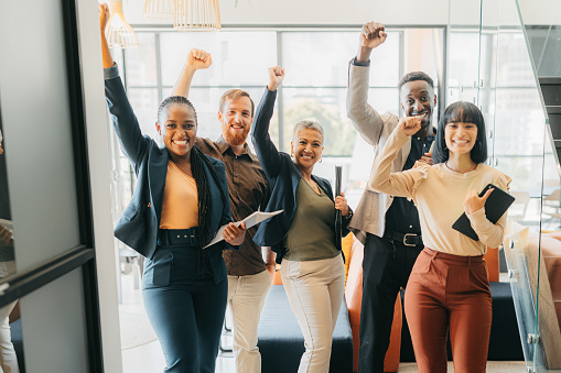 Portrait of a happy group of business people celebration or cheering while  in the office . Team of corporate professional workers celebrating goal, target and deadline while working in the workplace