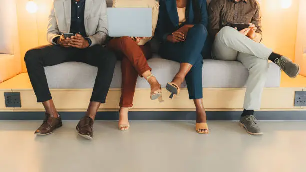 Photo of Job interview, we are hiring and business people waiting as potential office workers on a sofa. Team, staff and group online using technology to wait for a meeting with corporate management employees