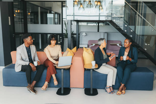 Collaboration, talking and business people working and being social in workplace sofa in creative multitasking meetings. Corporate worker team women in project conversation, planning or brainstorming