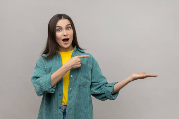 istock Surprised woman presenting copy space on her palm, showing empty place for commercial text or goods. 1426026762