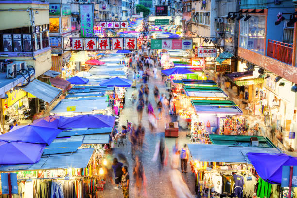 Rush hour shoppers in motion along busy Fa Yuen Street at night in Hong Kong Night market rush hour in busy Fa Yuen Street in Mong Kok, Hong Kong, China. Long exposure for crowd motion effect. mong kok stock pictures, royalty-free photos & images