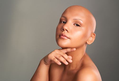 Cancer survivor, face and beauty of a model posing in healthy and beautiful skin against a grey background. Portrait of a woman in skincare wellness in support, advert or voice for cancerous patients
