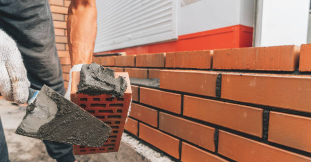 istock Builder applies cement mortar to red brick close up. Brick building concept 1426038422