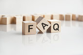 text faq on wooden blocks with letters on a white background. reflection of the caption on the mirrored surface of the table