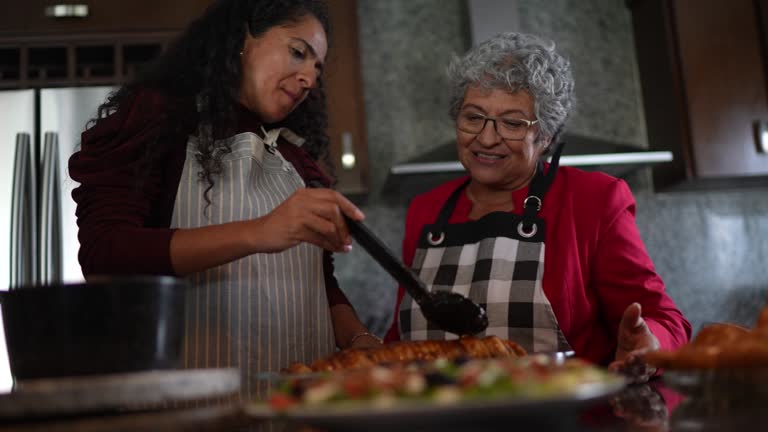 Senior woman with her daughter preparing food at kitchen counter at home