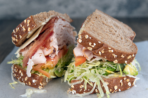 Lunch is served with a loaded turkey, bacon, and avocado sandwich overflowing with ingredients.