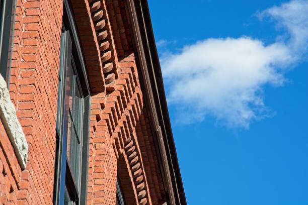 istock Decorative red brick cornice on 19th century textile mill building set against bright blue sky 1426048240
