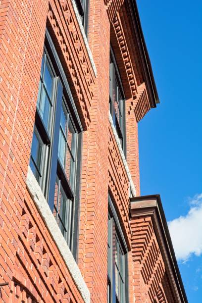 istock Decorative red brick cornice on 19th century textile mill building set against bright blue sky 1426048307