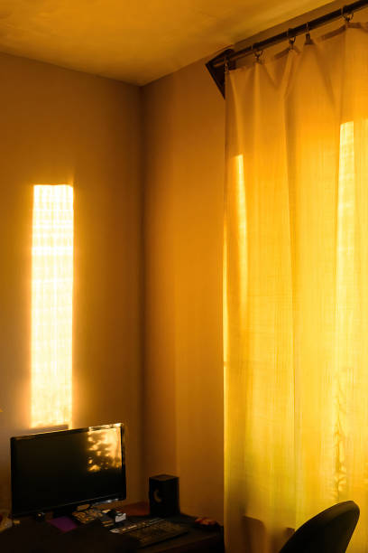 istock Sunbeams at sunset fall on computer desk in apartment. 1426049773