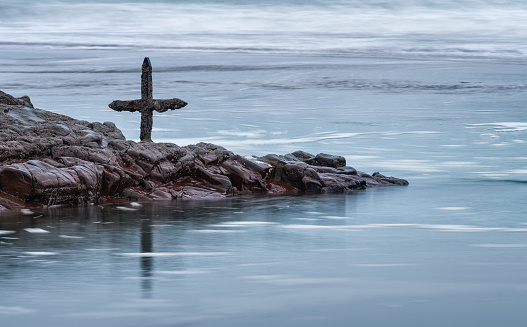 This old cross marks the half tide point at Summerleaze beach in Cornwall. For once, the sea is calm, with barely a ripple in the turquoise water, though farther out, the swells and eddies hint at undercurrents.