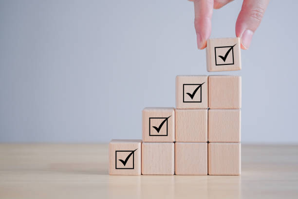 istock Checklist, Task list, Survey and assessment, Quality Control, Goals achievement and business success. Elections and Voting, Vote, to do list, Hand holding Check mark on ladder stack wooden blocks. 1426052979