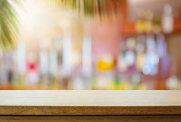 Empty wooden table on sunny blurred tropical bar background. Outdoor party mockup for design and product display.