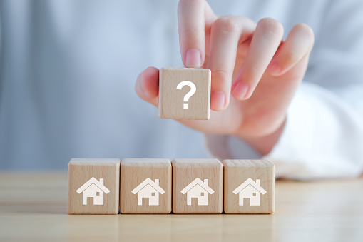 Real estate, Property investment and asset management concept. Hand holding question mark and house on wooden blocks. Decision to choose the best property with your right. Choosing suitable housing.