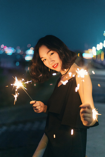 A woman having fun with a fireworks stick at night