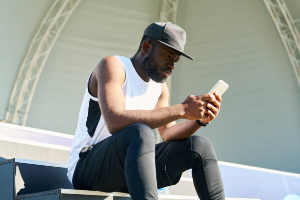 istock Young serious black man in activewear texting in smartphone on sunny morning 1426108201
