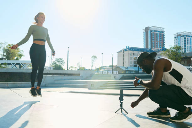 istock Happy young woman jumping over skipping rope while man shooting video 1426108487