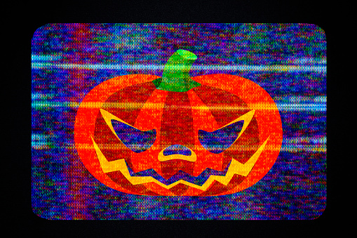 Close-up of Halloween pumpkin appearing on a broken TV.