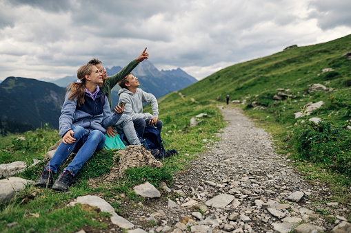 Three teenagers hiking in the high Austrian mountains - Alps, Vorarlberg, Austria. They are sitting, resting and checking names of the mountain peaks on smartphone.
Canon R5