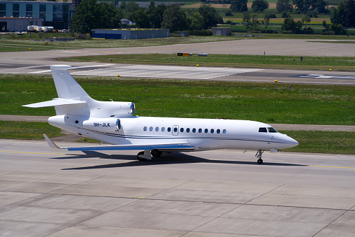 White private jet type Dassault Falcon 7X register 9H-JLK taxiing to runway at Zürich Airport on a sunny summer day. Photo taken July 15th, 2022, Zurich, Switzerland.