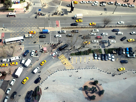 Aerial view of the city traffics at the center. Vehicles are moving on the road between buildings