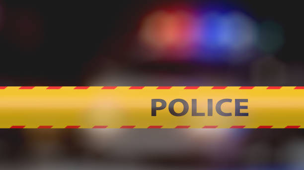 istock Crime scene police tape with police car background 1426113708