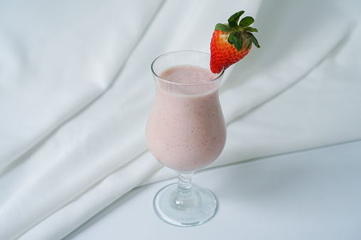 A glass of strawberry blended with banana on white background.