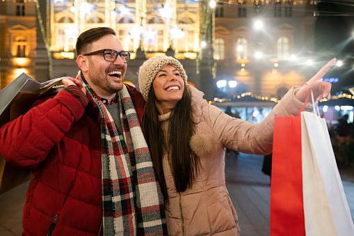 Happy couple having fun together on Christmas shopping outdoor. Holiday present people happiness concept