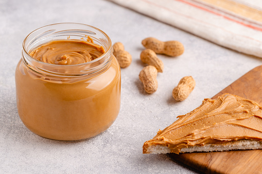 Peanut paste in an open jar and toast