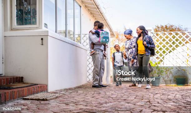 Parents Greeting Their Three Smiling Children After School Stock Photo - Download Image Now