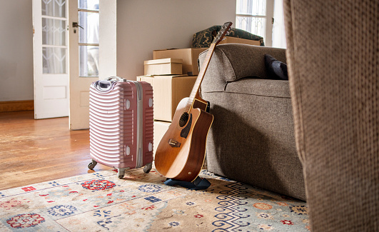 Guitar leaning on a sofa in a living room with packed boxes in the background on moving day