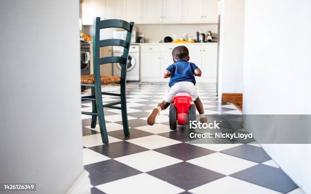 Little Boy Riding His Toy Tricycle In A Kitchen Stock Photo - Download Image Now - Rear View, Child, Domestic Life