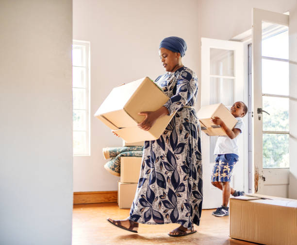 Woman and young son carrying boxes into their new home