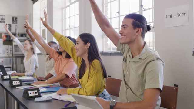 Hands up of college or university students to answer a question in class while learning in a maths lesson. Group of clever, smart or intelligent young people in a classroom ready to share knowledge
