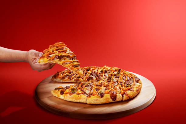 Hand taking a slice of pizza with beef and a cheese sauce