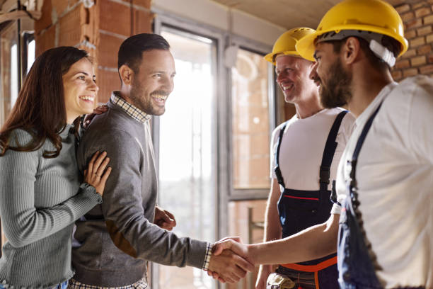 istock Happy manual workers greeting couple at construction site. 1426135442