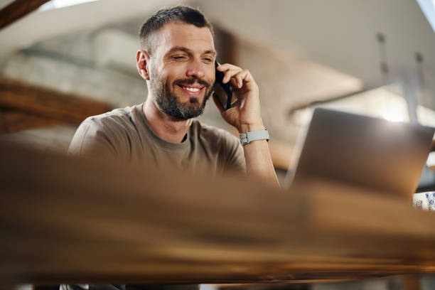 istock Happy man on the phone using laptop at home. 1426137456