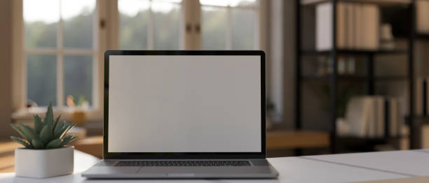 istock Laptop mockup on white working table over blurred home working room background. 1426138882