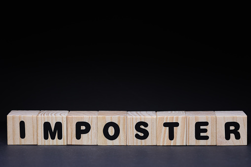 Word imposter from wooden blocks on black background