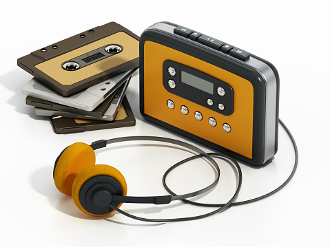 Vintage personal audio cassette player with yellow headphones and analogue audio cassettes.