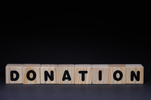 Word donation from wooden blocks on black background