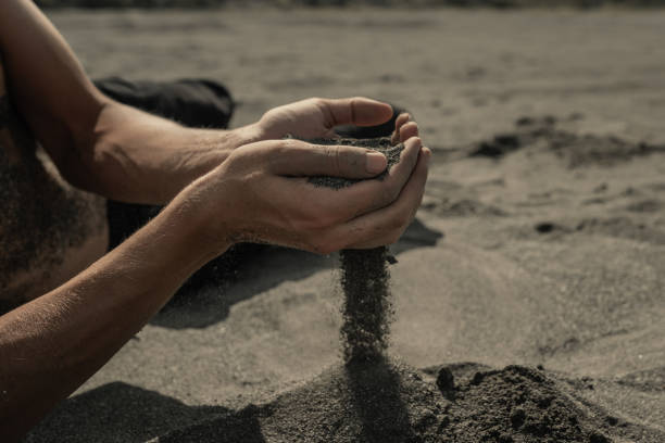 istock Man pouring sand through hands in desert 1426145489