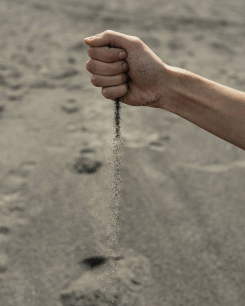 istock Man pouring sand through hand in desert 1426145538